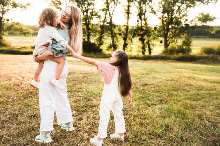 Blonde mother with two cute daughters are walking and having fun outdoors. Stylish, casual clothes.の写真素材