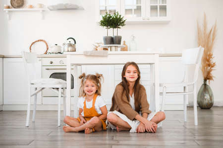 Two sisters play in a bright, stylish kitchen. Beautiful interior.の写真素材
