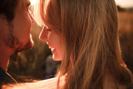 A young couple cuddles in the sunset rays of the summer sun. Real emotions and romance.