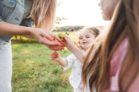 Blonde mother with two cute daughters are walking and having fun outdoors. Stylish, casual clothes.