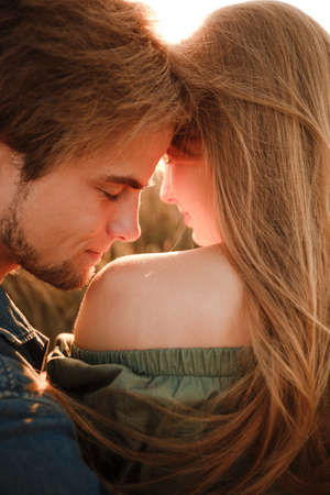 A young couple cuddles in the sunset rays of the summer sun. Real emotions and romance.