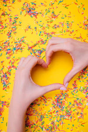 Female hands and confetti on a yellow background. Trends