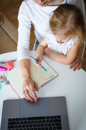 Work at home during quarantine. Mom with a child. Distant work education