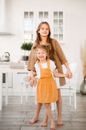 Two sisters play in a bright, stylish kitchen. Beautiful interior.の写真素材