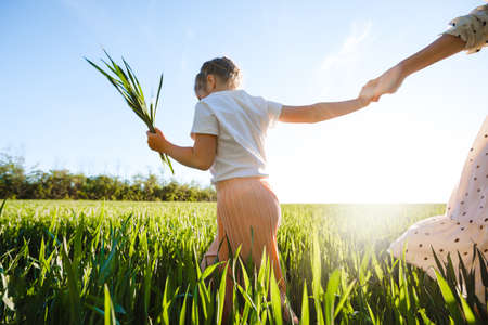 A mother with two daughters is walking in a green field. Hugs and feelings.の写真素材