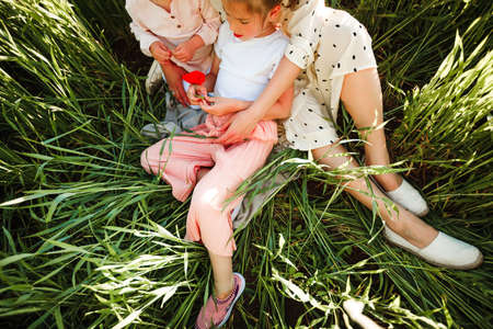 A mother with two daughters is walking in a green field. Hugs and feelings.