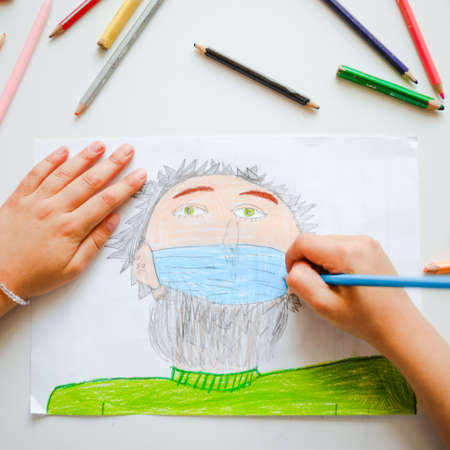The child paints a person in a medical mask. Pandemic concept.の写真素材