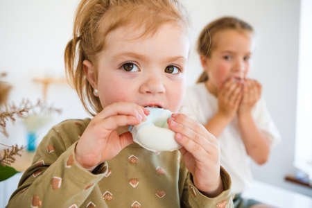 Little girls play in the kitchen and eat sweets.の写真素材