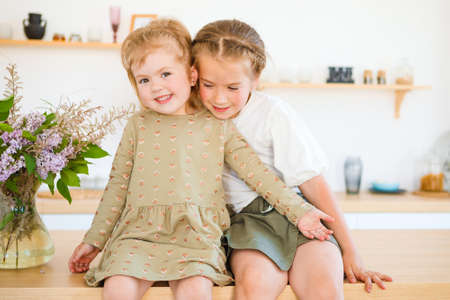 Little girls play in the kitchen and eat sweets.
