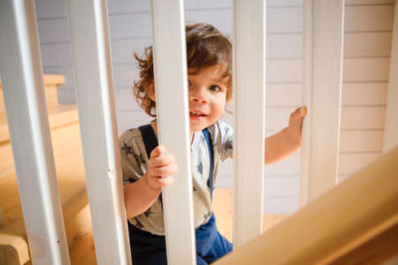 The kid looks out through the railing of the wooden staircase.の写真素材