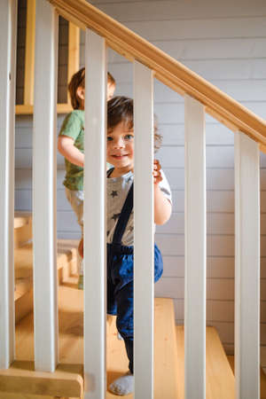 The kid looks out through the railing of the wooden staircase.の写真素材