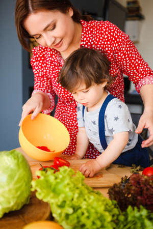 Mom and sons are cook vegetarian food in a stylish kitchen.の写真素材
