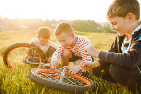 School-age boys ride a bicycle in a meadow.の写真素材