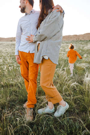 A hipster family walks in a summer field.