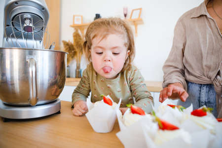 Mom and daughter are baking a beautiful dessert with cream.の写真素材