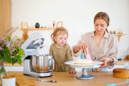 Mom and daughter are baking a beautiful dessert with cream.の写真素材