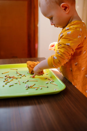 Toddler plays with modeling dough with small objects. sensory skills.の写真素材