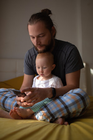 Dad and child are watching content on the phone. home rest.の写真素材