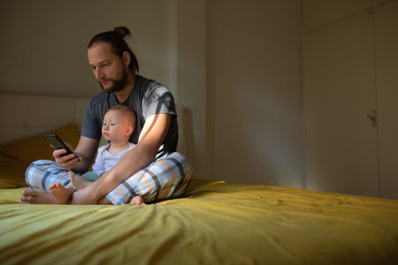 Dad and child are watching content on the phone. home rest.の写真素材