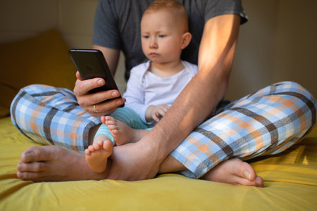 Dad and child are watching content on the phone. home rest.の写真素材