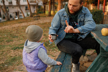 Dad and child have a picnic in the city park. Wooden table and bench.の写真素材