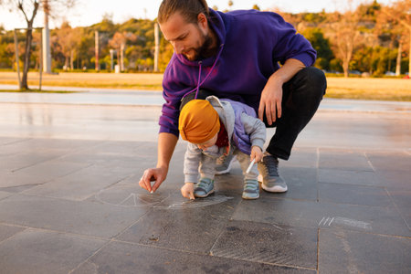 Dad and child draw with chalk on the pavement. autumn day.の写真素材