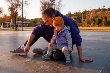 Dad and child draw with chalk on the pavement. autumn day.の写真素材