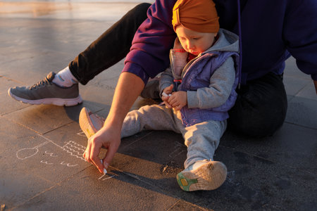 Dad and child draw with chalk on the pavement. autumn day.の写真素材