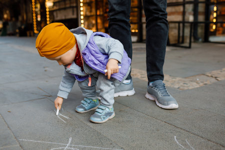 Dad and child draw with chalk on the pavement. autumn day.の写真素材