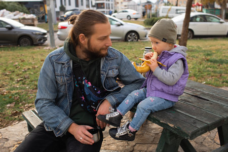 Dad and child have a picnic in the city park. Wooden table and bench.の写真素材