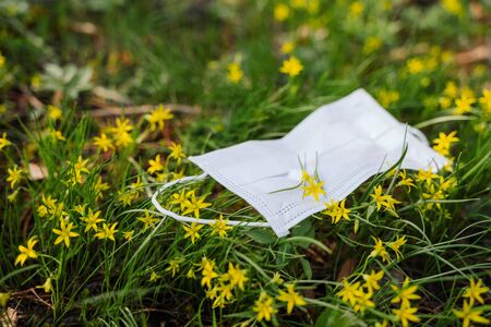 the protective mask is lying on the grass, on the mask is a flower. spring during the coronavirusの写真素材