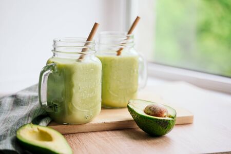 creamy smoothie from avocado and banana in glass cups with paper tubes on a light background. no plastic. healthy foodの写真素材