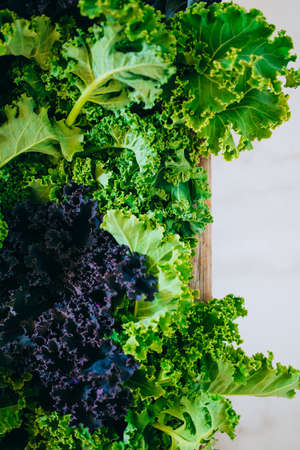 Fresh green and purple kale in a wooden box on a marble backgroundの写真素材