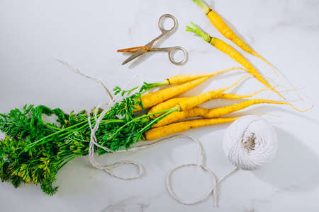 Fresh washed yellow carrots with a tops on a marble background, flat lay, top viewの写真素材