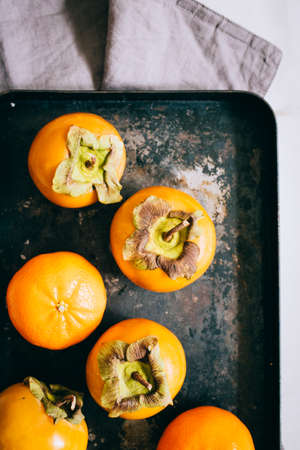 Persimmon and tangerine in black tray on a marble background