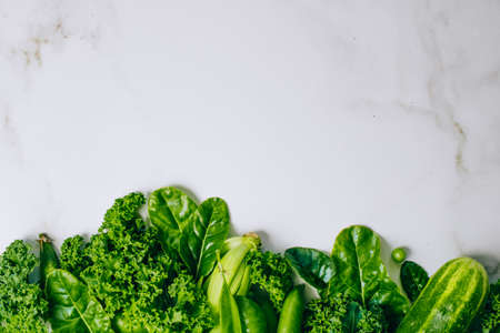 Frame of fresh green vegetables on a marble background, copy space, flay lay, top viewの写真素材