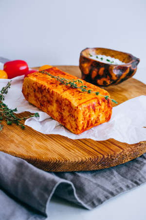 Cheese halumi with smoked paprika on a wooden board with tomatoes, and thymeの写真素材