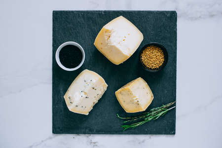 Assorted Ñachotta cheese with black cumin, fenugreek and herbs on black shale