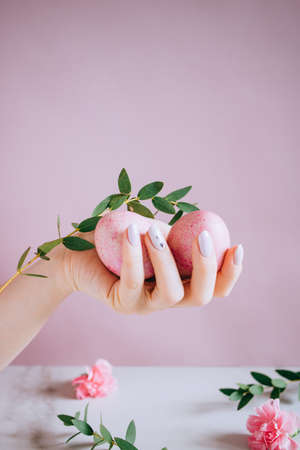 The girl is holding in hand a pink easter egg, pink and marble background, minimalism, flowersの写真素材