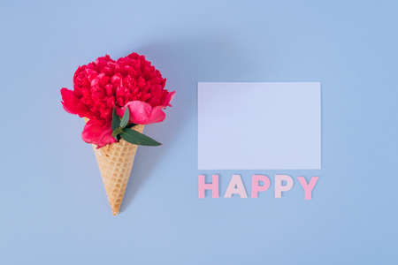 Flat lay Ice Cream Cone with pink peony on blue background and white clear blank. Happy textの写真素材