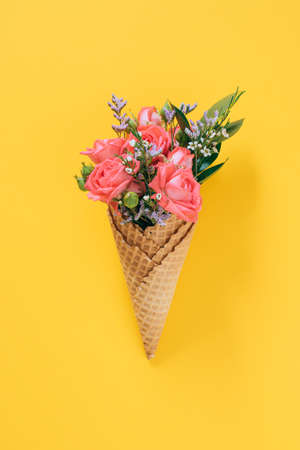 Flat lay Ice Cream Cones with colorful bouquet on yellow background, copy spaceの写真素材
