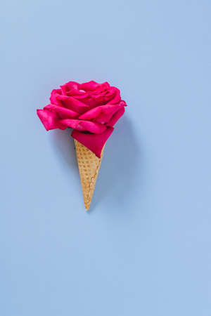 Flat lay Ice Cream Cone with pink rose on blue background, copy spaceの写真素材