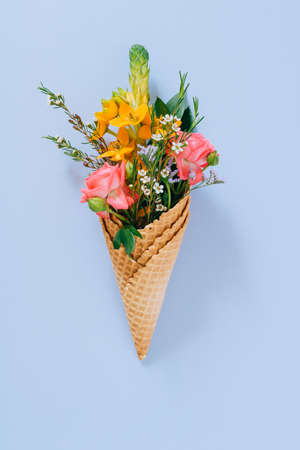 Flat lay Ice Cream Cones with colorful bouquet on blue background, copy spaceの写真素材