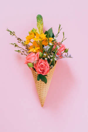 Flat lay Ice Cream Cones with colorful bouquet on pink background, copy spaceの写真素材