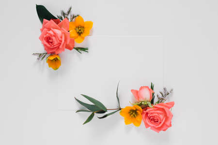 Flat lay bright creative frame of fresh flowers and leaves with white clean blank for text, natural backgroundの写真素材