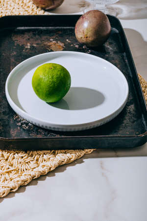 Tropical style lime on a blue plate and passion fruit. Fresh and colorful conceptの写真素材