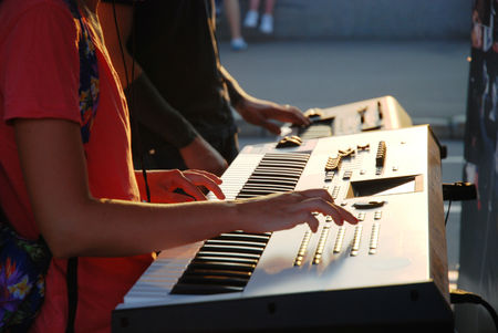 Golden hour at sunset gay and girl playing on a synthesizer.の写真素材