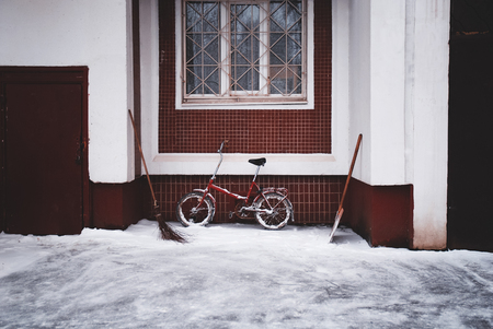 Bike in a snow near the wall of buildingの写真素材