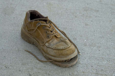 Old torn work shoe on the street.の写真素材