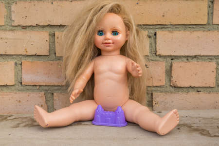 An old dirty undressed doll is sitting. Coronovirus self-isolation conceptの写真素材